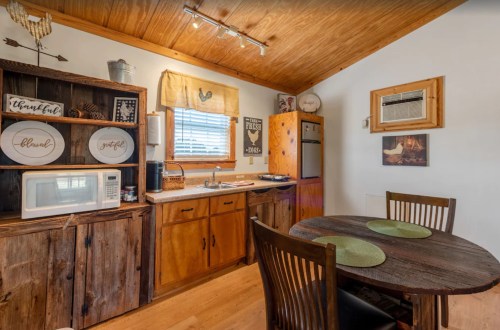 Cozy kitchen with wooden cabinets, a round dining table, and modern appliances under a sloped ceiling.