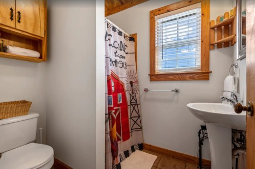 A cozy bathroom featuring a shower with a colorful curtain, a sink, and wooden accents.