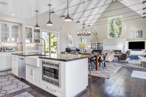 Bright, modern kitchen with an island, open to a spacious living area featuring high ceilings and large windows.