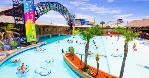 A vibrant water park scene with a lazy river, colorful slides, and people enjoying the water under a clear blue sky.