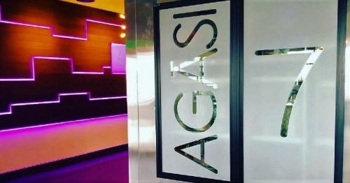 A modern interior with a wall featuring purple lighting and a sign displaying "AGASI 7."