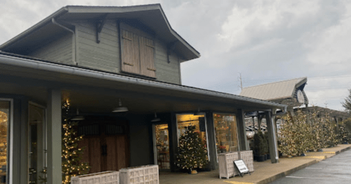 A cozy building with a wooden facade, decorated with Christmas trees and lights, under a cloudy sky.