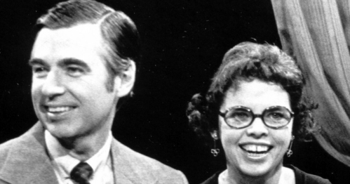 A black and white image of a man and woman smiling together on a television set.