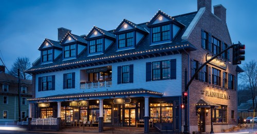 A charming, illuminated restaurant building at dusk, featuring a classic design and outdoor seating.