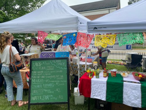 A vibrant outdoor market scene with food stalls, colorful decorations, and people enjoying the atmosphere.