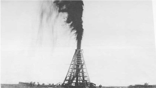Black and white image of an oil well gushing black oil into the air, with workers nearby.