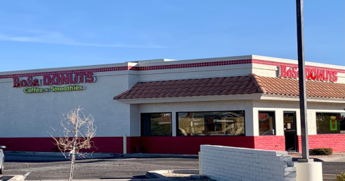 A storefront of Bo's Donuts featuring a sign for coffee and smoothies, with a clear blue sky in the background.
