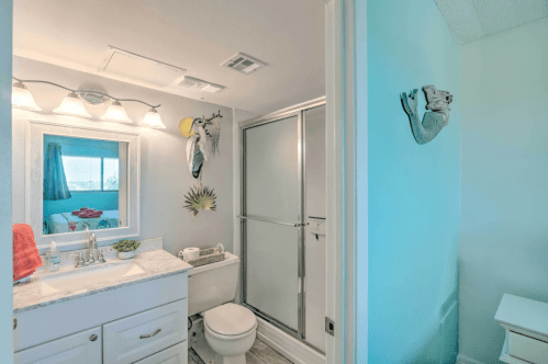 Bright bathroom featuring a shower, vanity with a mirror, and decorative accents in a light color scheme.