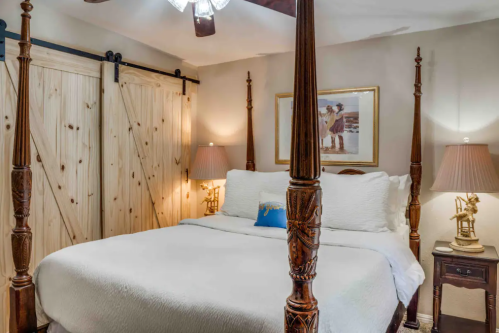 Cozy bedroom featuring a four-poster bed, wooden sliding doors, and warm lighting from bedside lamps.