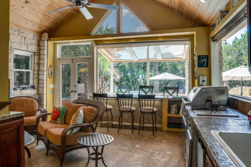 Cozy kitchen area with a view, featuring a seating area, bar stools, and large windows overlooking a patio.