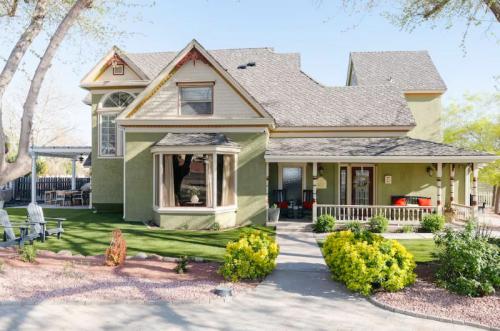 A charming green house with a porch, surrounded by landscaped gardens and a pathway.