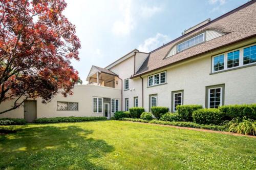 A spacious backyard with a well-maintained lawn, surrounded by shrubs and a large house with multiple windows.