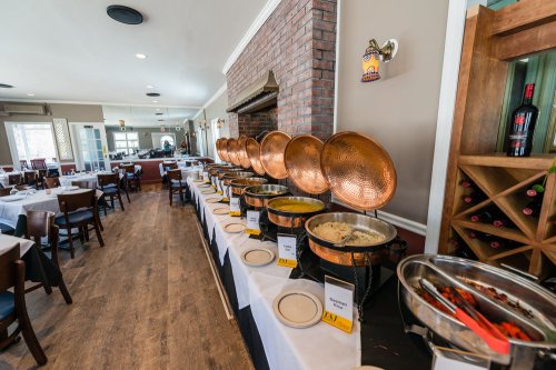 A buffet setup with copper chafing dishes, white tablecloths, and a cozy restaurant interior.