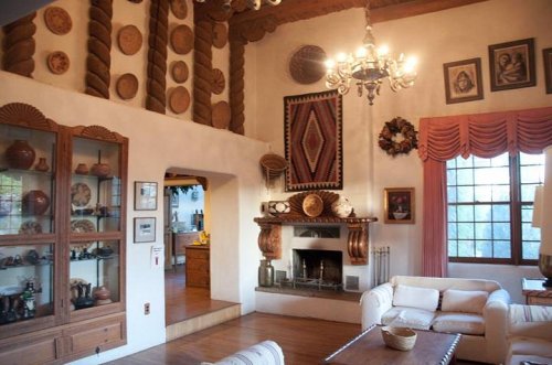 Cozy living room with a fireplace, decorative pottery, wooden beams, and warm lighting.