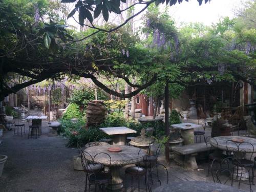 A serene garden with stone tables and chairs, surrounded by lush greenery and hanging wisteria flowers.