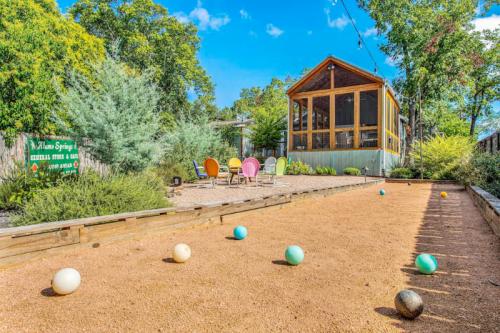 A bocce ball court with colorful chairs and a screened porch surrounded by greenery.