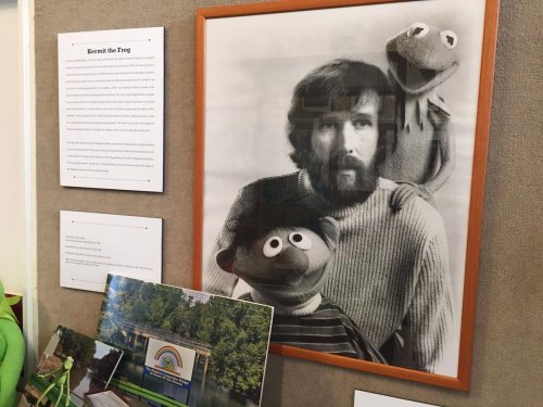Black and white photo of a man with a beard, holding Kermit the Frog and Ernie puppets, displayed with informational text.