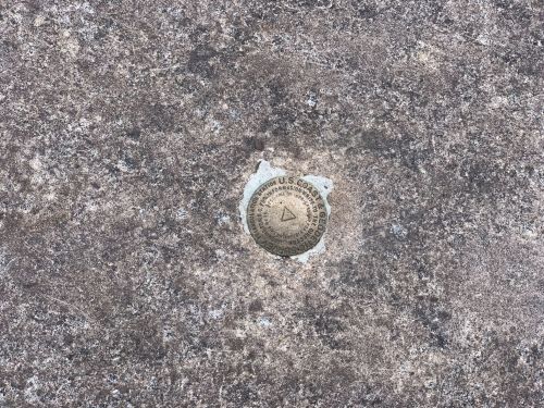 A metal survey marker embedded in a concrete surface, displaying the U.S. Geological Survey emblem.