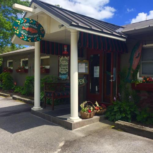 A charming restaurant with a sign reading "Lakeside Restaurant," featuring a welcoming entrance and colorful flower pots.