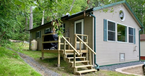 a quaint lakeside rental in vermont with wooden steps and green trees surrounding