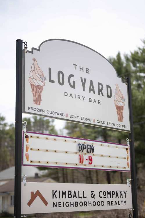 Sign for "The Log Yard Dairy Bar" featuring frozen custard, soft serve, and cold brew coffee, with an "Open" message.