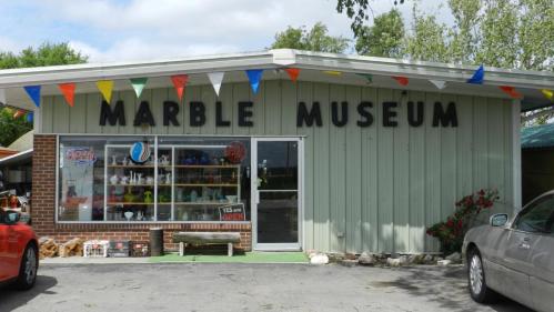 Exterior of the Marble Museum, featuring a green building with large letters and colorful flags.