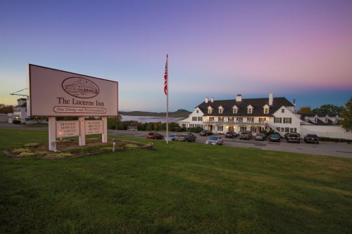 The Lucerne Inn at dusk, featuring a sign, American flag, and scenic views of the surrounding landscape.