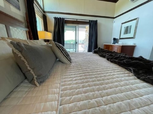 Cozy bedroom with a neatly made bed, decorative pillows, and large windows overlooking a balcony.