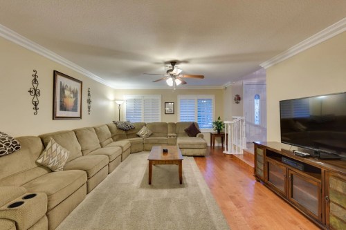 Cozy living room with a large sectional sofa, wooden coffee table, TV stand, and soft lighting.
