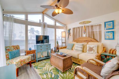 Cozy living room with tropical decor, a large window, a TV, and comfortable seating. Bright and inviting atmosphere.