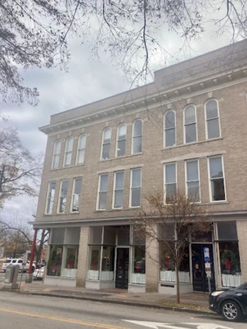 A three-story brick building with large windows, featuring holiday decorations on the ground floor.