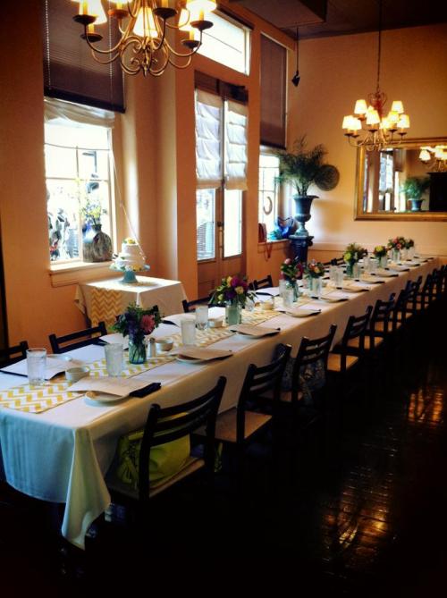 A long dining table set with flowers and tableware in a warmly lit restaurant.