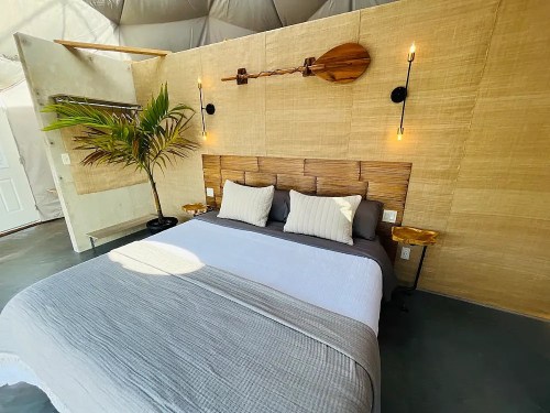 Cozy bedroom with a gray and white bedspread, wooden accents, and a decorative paddle on the wall.