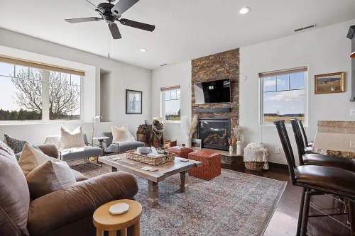Cozy living room with a stone fireplace, comfortable seating, and large windows showcasing a scenic view.