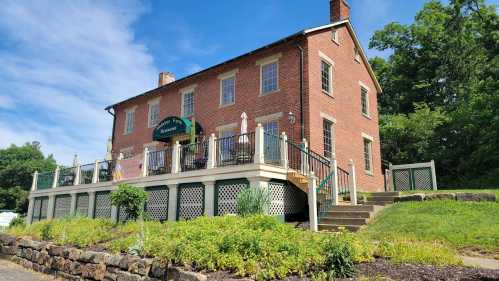 A brick building with a green awning, surrounded by greenery and a patio with steps leading up to it.