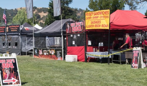 Food vendor tents at an outdoor event, featuring BBQ and seafood options, with a sign for "Big Joe's BBQ."