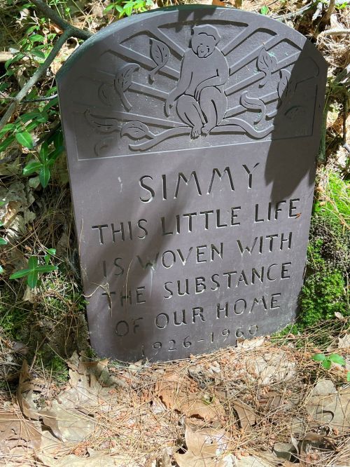 A memorial plaque reading "Simmy: This little life is woven with the substance of our home, 1926-1960," surrounded by nature.