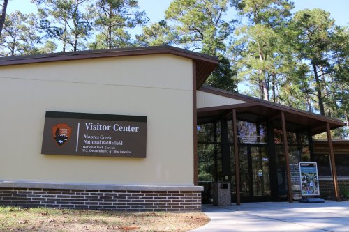Exterior of the Moores Creek National Battlefield Visitor Center, featuring a sign and surrounded by trees.