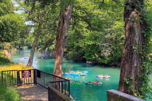 A serene river scene with people floating on colorful tubes, surrounded by lush greenery and tall trees.
