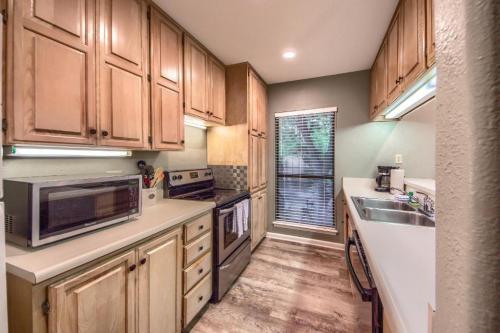 A modern kitchen with wooden cabinets, stainless steel appliances, and a window overlooking greenery.