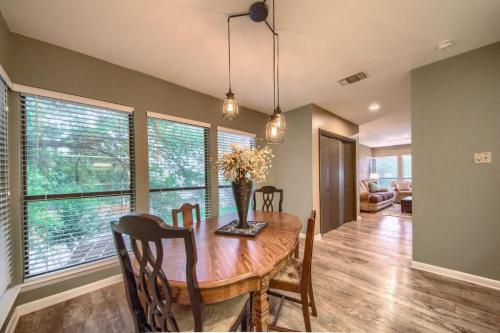 A cozy dining area with a wooden table, chairs, and large windows overlooking greenery. Soft lighting enhances the space.