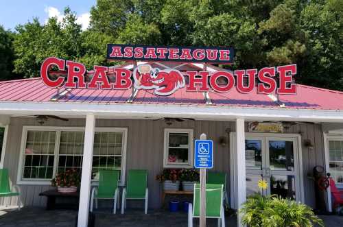 Sign for Assateague Crab House with a cartoon crab, featuring a red roof and green chairs outside.