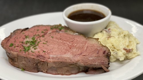 A plate featuring a slice of roast beef with gravy and a side of creamy mashed potatoes.