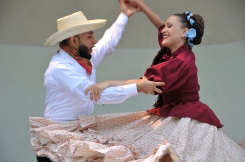A man and woman dance together in traditional attire, showcasing vibrant movements and cultural celebration.