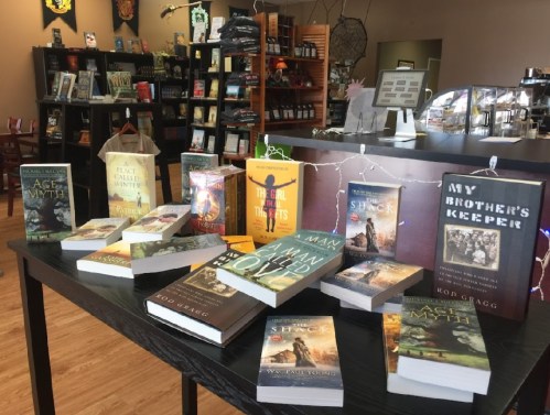 A display of various books on a table in a cozy bookstore, with shelves of books in the background.