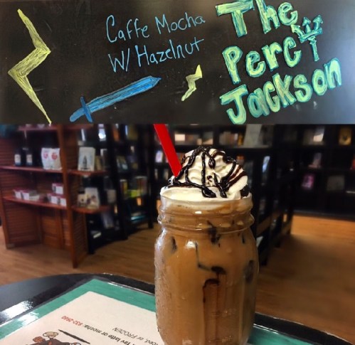 A jar of iced caffe mocha topped with whipped cream and chocolate drizzle, with a colorful sign reading "The Percy Jackson."