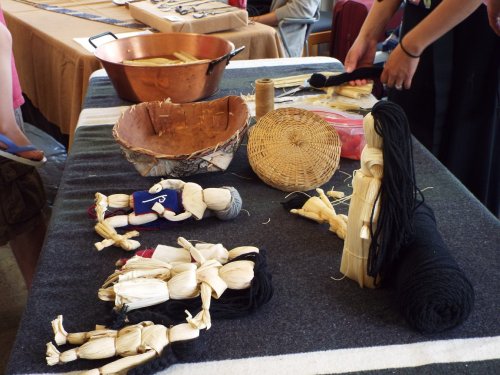 A table displays handmade dolls, woven baskets, and crafting materials, showcasing traditional art and culture.