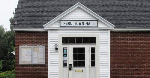 Exterior of Peru Town Hall, featuring a brick facade and a sign above the entrance.