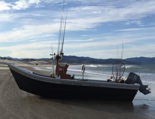 A fishing boat on a sandy beach with fishing rods and equipment, against a backdrop of waves and mountains.