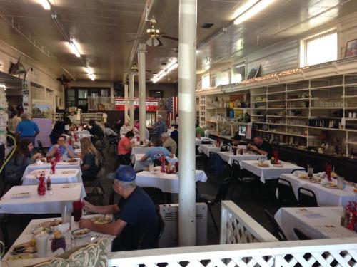 A spacious dining area with tables set for meals, patrons eating, and decor featuring vintage items and American flags.